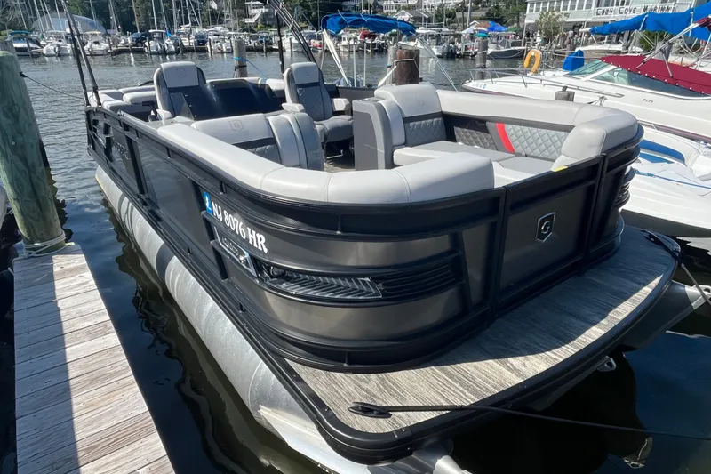 Slide: The Image of 2022 Godfrey AquaPatio 235 ULC pontoon boat docked at marina, featuring luxurious seating. - 1
