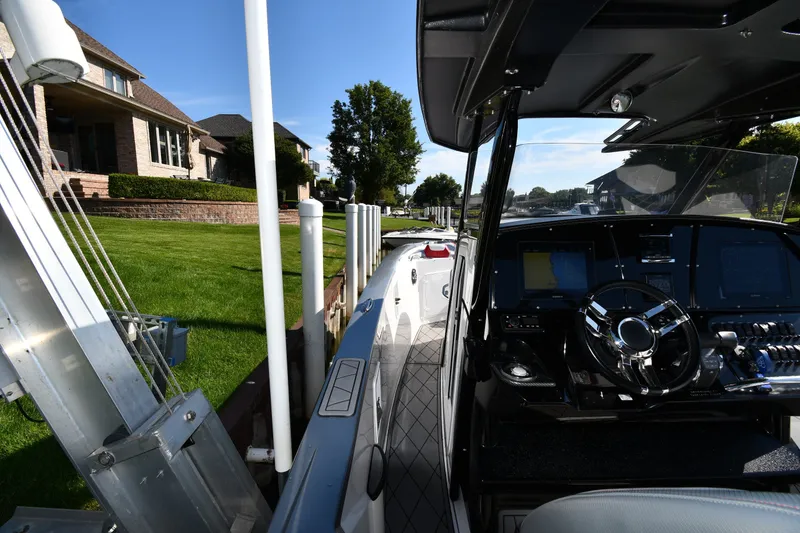 Slide: The Image of 2017 Sunsation 32 CCX boat docked near waterfront homes, showcasing sleek interior and controls. - 19