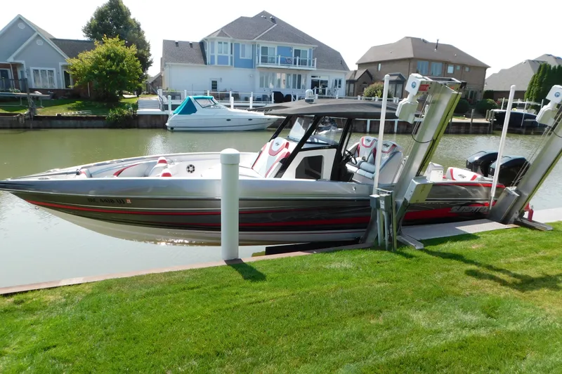 The Image of 2017 Sunsation 32 CCX boat docked by waterfront homes, featuring sleek design and modern amenities. - 0