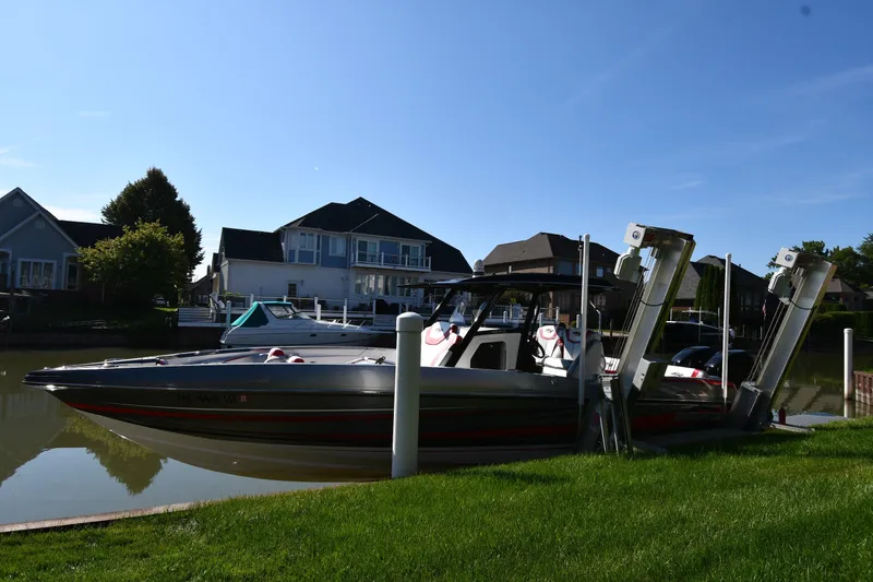 The Image of 2017 Sunsation 32 CCX boat docked by waterfront homes under clear blue sky. - 1
