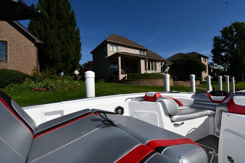 Slide: The Image of 2017 Sunsation 32 CCX boat interior with red and gray seating, docked near residential homes. - 21