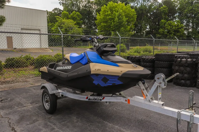 The Image of 2025 Sea-Doo Spark Trixx for 1 on trailer, parked outdoors near fence and tires. - 1