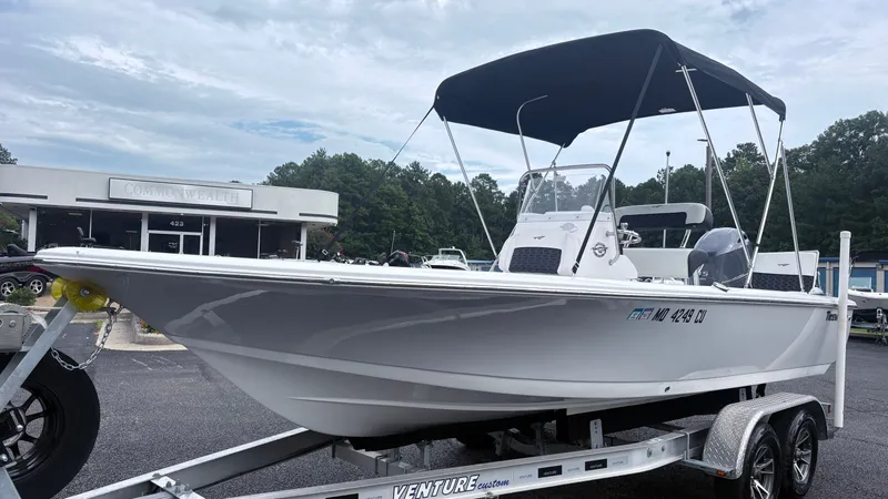 The Image of A 2024 Tidewater 1910 Bay Max boat on a trailer, featuring a black sunshade and modern helm console. - 1