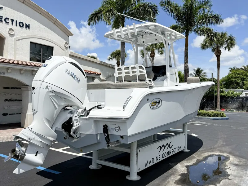 Slide: The Image of 2027 Sea Hunt Ultra 229 on display stand, with palm trees in the background. - 8