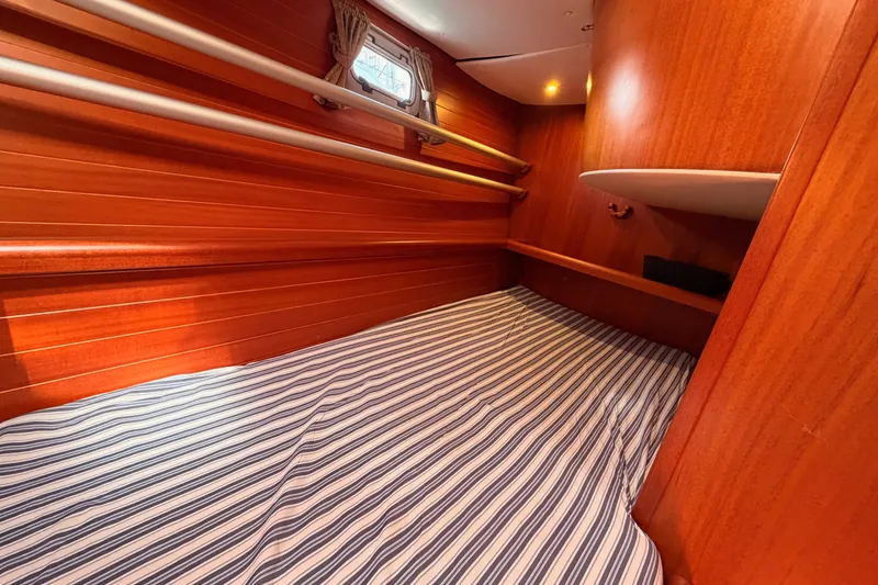 Slide: The Image of Cozy cabin interior of 2003 Farr 50 Pilot House with striped bedding and wooden finish. - 76