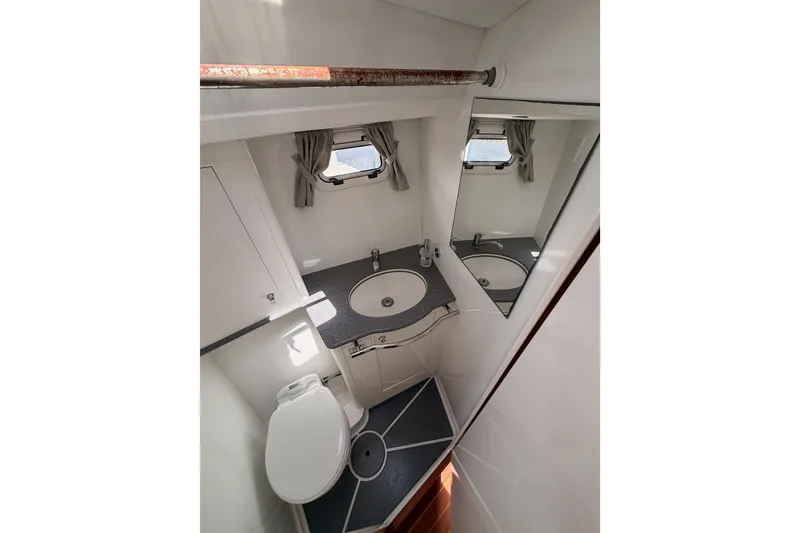 Slide: The Image of Compact bathroom in a 2003 Farr 50 Pilot House yacht, featuring a sink, toilet, and mirror. - 80