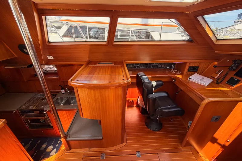 Slide: The Image of 2003 Farr 50 Pilot House interior with wooden finish, navigation desk, and seating. - 62