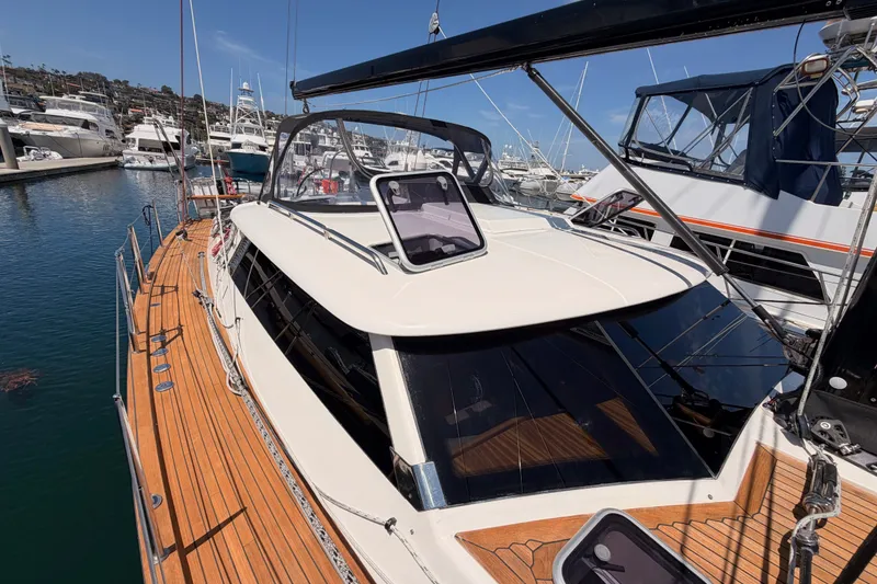 Slide: The Image of 2003 Farr 50 Pilot House yacht docked in a marina, showcasing sleek design and wooden deck. - 32