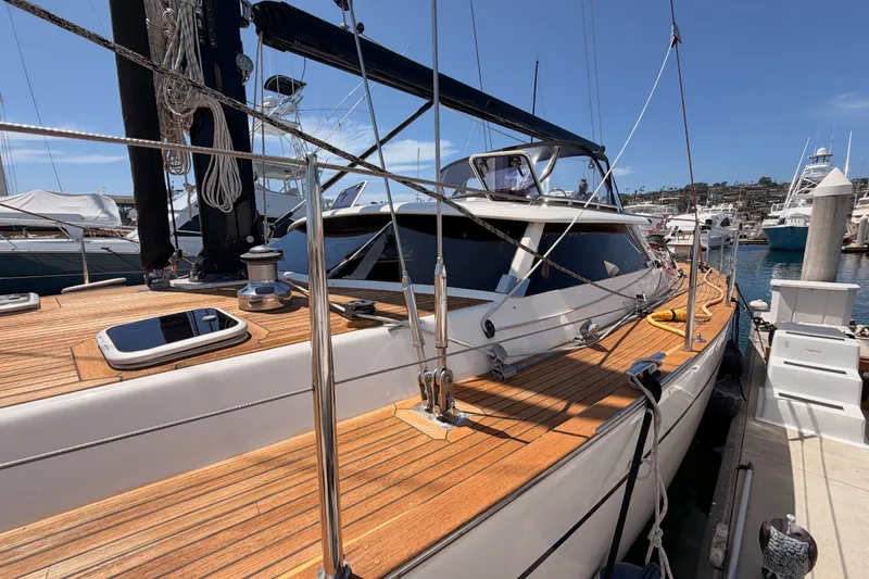 Slide: The Image of 2003 Farr 50 Pilot House yacht docked, showcasing sleek design and wooden deck. - 16