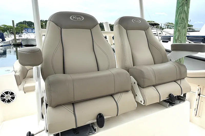 Slide: The Image of 2024 Key West 263 FS boat seats at marina, featuring comfortable beige upholstery. - 13