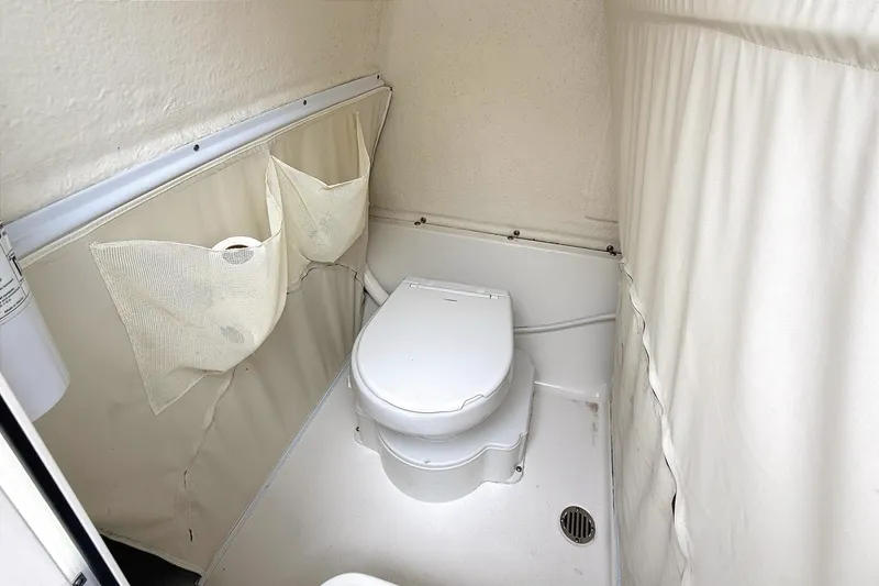 Slide: The Image of 2024 Key West 263 FS boat interior bathroom with toilet and storage pockets. - 29