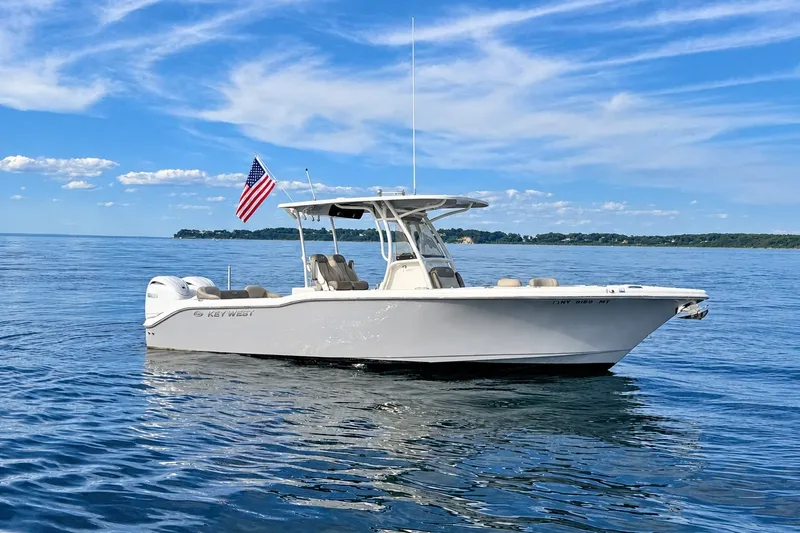 The Image of 2024 Key West 263 FS boat on calm water with American flag, clear sky background. - 0