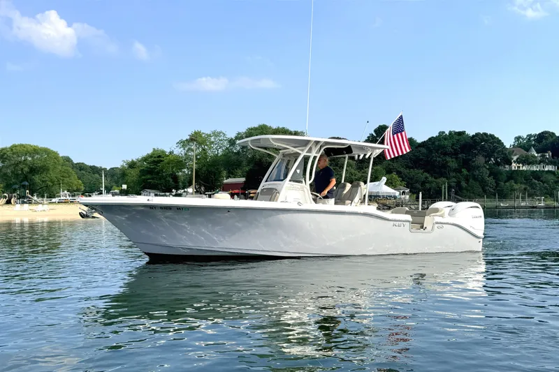 Slide: The Image of A 2024 Key West 263 FS boat on calm water with an American flag at the stern. - 1