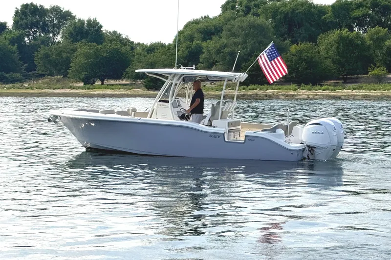 Slide: The Image of A 2024 Key West 263 FS boat on calm water with an American flag at the stern. - 4