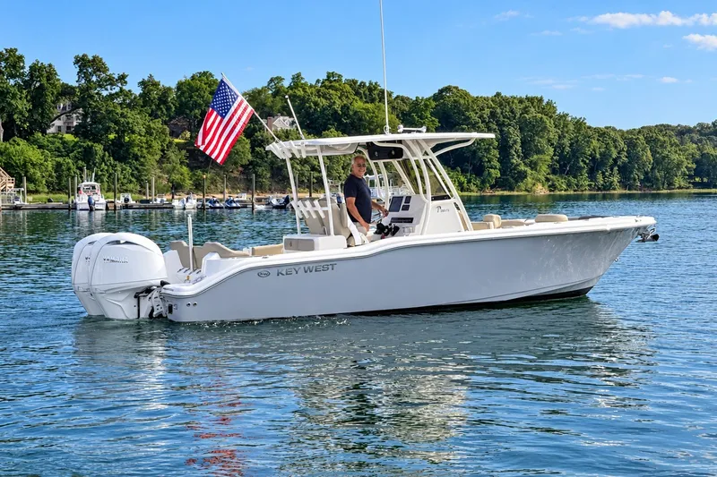 Slide: The Image of 2024 Key West 263 FS boat on water with American flag, surrounded by trees. - 1