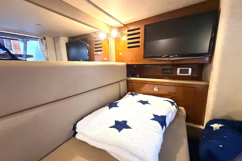 Slide: The Image of Interior of 2013 Sea Ray Sundancer 370 with cozy bed, TV, and star-patterned blanket. - 24