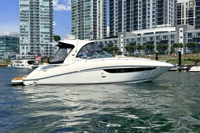 The Image of 2013 Sea Ray Sundancer 370 yacht cruising near modern city skyline. - 0