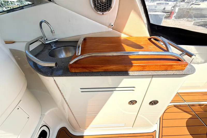 Slide: The Image of 2013 Sea Ray Sundancer 370 yacht kitchenette with sink, wooden cutting board, and storage cabinets. - 8