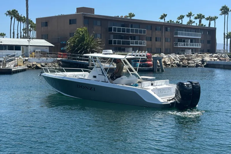 Slide: The Image of 2007 Donzi 35 ZF Cuddy boat docked in a marina with palm trees. - 1