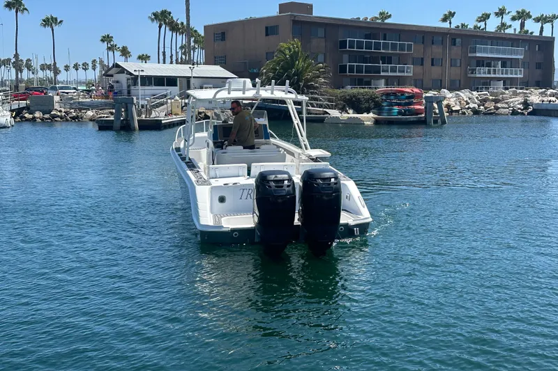 Slide: The Image of 2007 Donzi 35 ZF Cuddy boat navigating a marina with palm trees and buildings. - 3