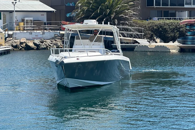 Slide: The Image of 2007 Donzi 35 ZF Cuddy boat cruising in a marina with clear blue water. - 2