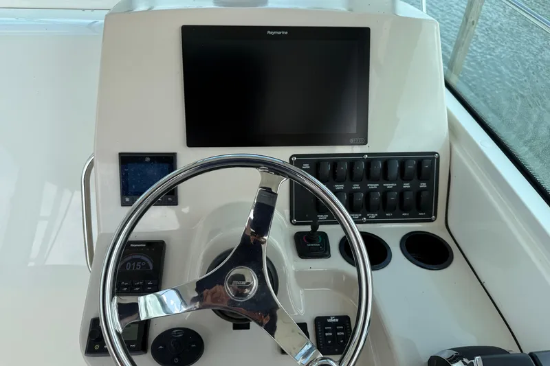 Slide: The Image of 2020 Boston Whaler 285 Conquest helm with steering wheel and electronic controls. - 13