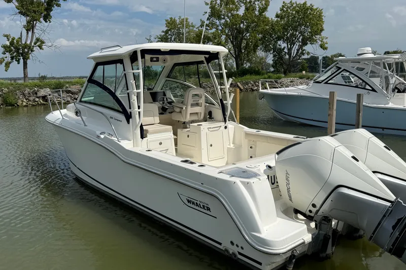 The Image of 2020 Boston Whaler 285 Conquest boat docked in a serene marina setting. - 0