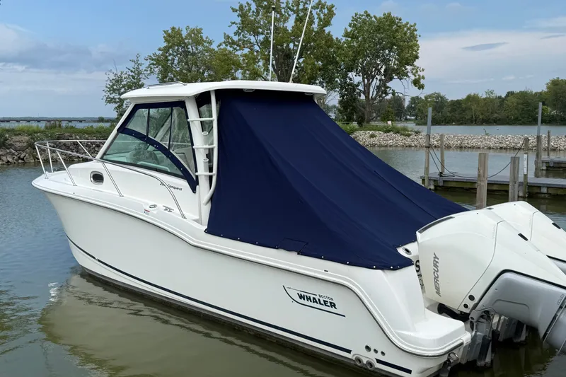 Slide: The Image of 2020 Boston Whaler 285 Conquest boat docked with blue cover and twin Mercury engines. - 1