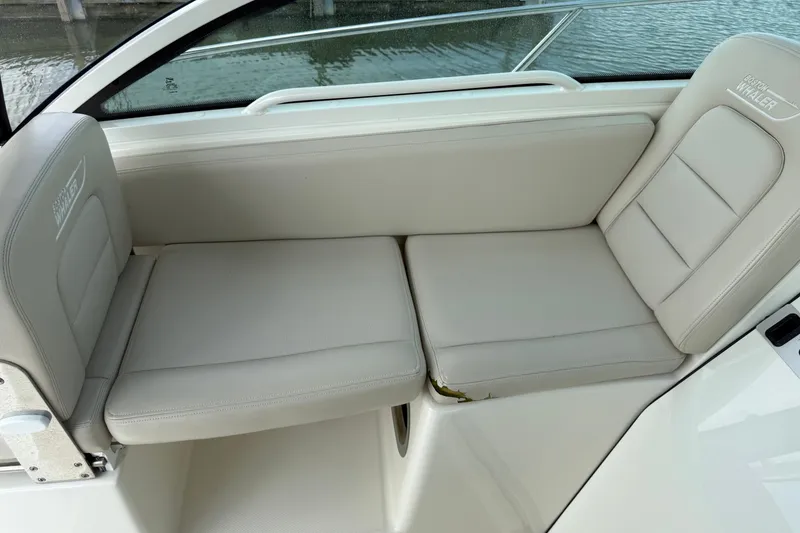 Slide: The Image of 2020 Boston Whaler 285 Conquest boat seating with beige cushions by the water. - 18