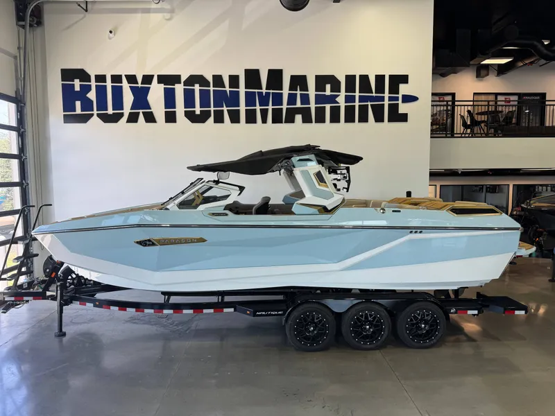 The Image of A sleek, light blue boat with a modern design sits on a trailer in a showroom. - 1