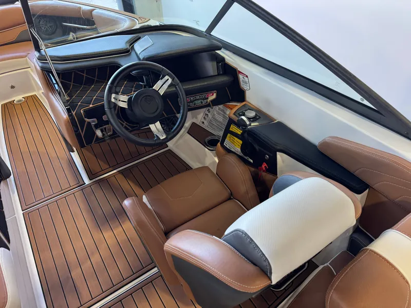 Slide: The Image of The image shows the cockpit of a 2018 Nautique Super Air Nautique GS22 with brown leather seats and a modern dashboard. - 25