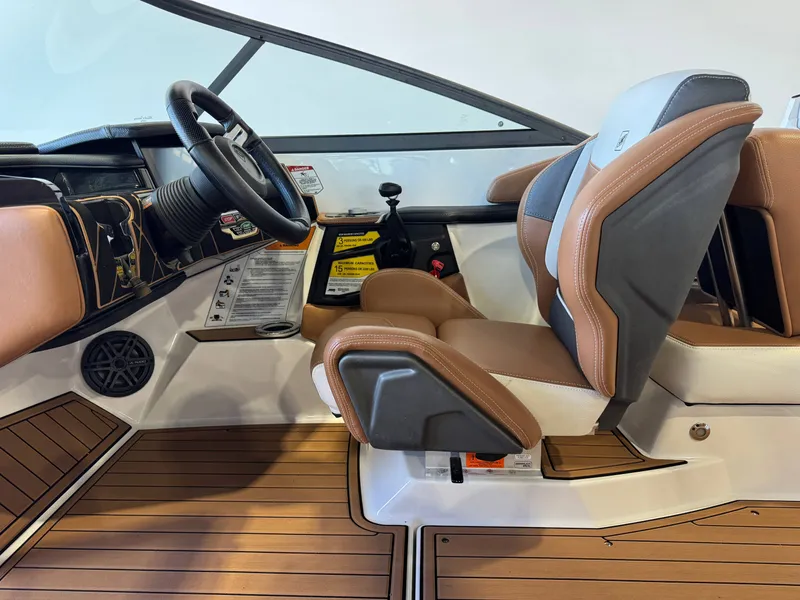 Slide: The Image of The image shows the helm of a 2018 Nautique Super Air Nautique GS22 with brown and gray seats. - 23