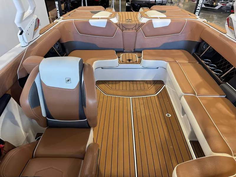 Slide: The Image of The image shows the interior of a 2018 Nautique Super Air Nautique GS22 with brown leather seats and wood flooring. - 22