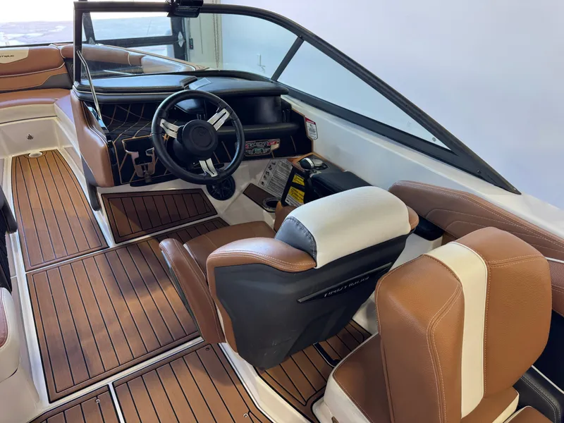 Slide: The Image of The image shows the cockpit of a 2018 Nautique Super Air Nautique GS22 with brown leather seats. - 24