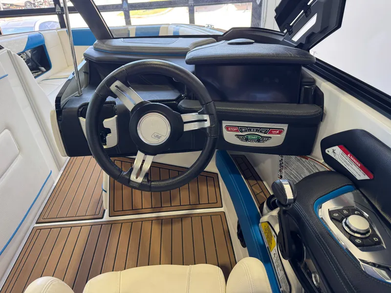 Slide: The Image of The image shows the cockpit of a 2020 Nautique Super Air Nautique G23 with a modern steering wheel and wood flooring. - 26