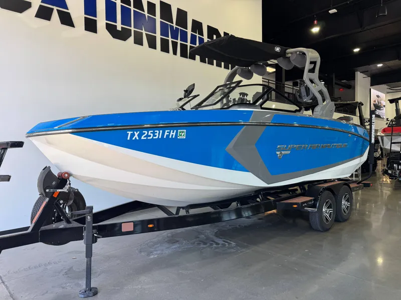 Slide: The Image of A blue and white 2020 Nautique Super Air Nautique G23 on a trailer in a showroom. - 2