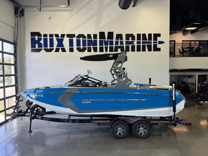 The Image of A blue and white 2020 Super Air Nautique G23 boat on a trailer in a showroom. - 1
