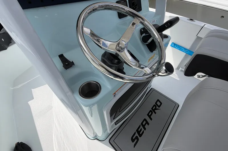 Slide: The Image of Steering console of 2026 Sea Pro 245FLXR Sandbar boat with chrome wheel and cup holders. - 25