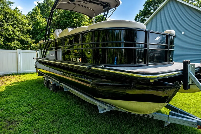 Slide: The Image of 2018 Starcraft SLS 5 Q pontoon boat on trailer, parked on grass beside a house. - 7