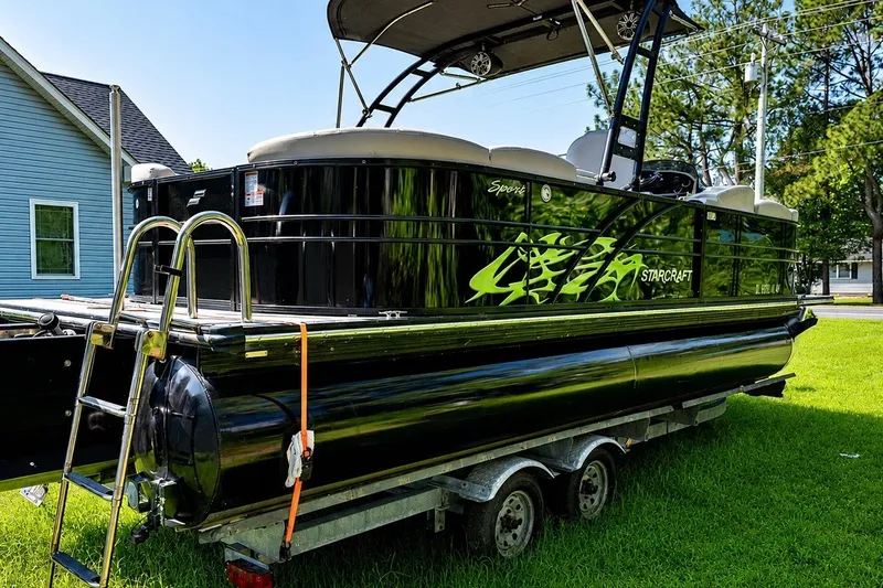 Slide: The Image of 2018 Starcraft SLS 5 Q pontoon boat on trailer, parked on grass. - 2