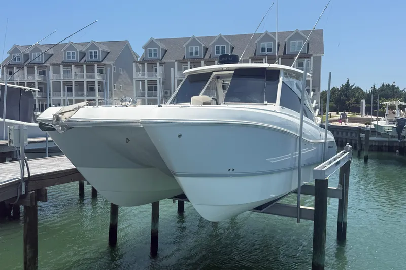 The Image of 2022 World Cat 325 DC boat docked at marina with waterfront buildings in background. - 1