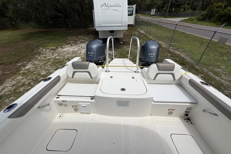 Slide: The Image of 2022 World Cat 230 DC boat interior with twin Yamaha 115 engines, parked near a road. - 48