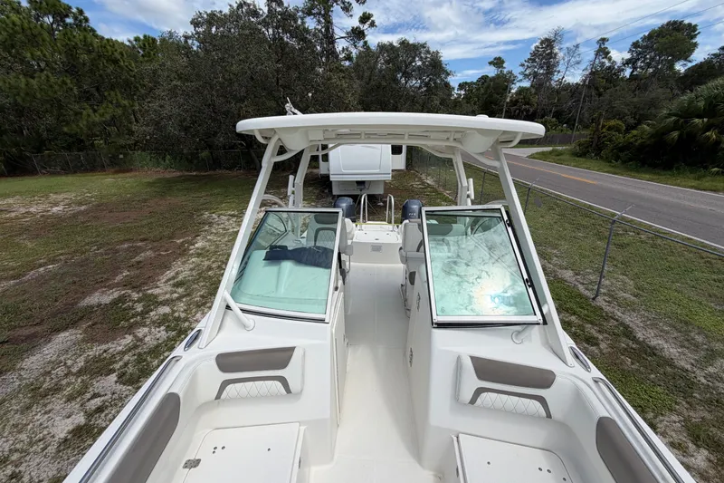 Slide: The Image of 2022 World Cat 230 DC boat on land, surrounded by trees and a road. - 63