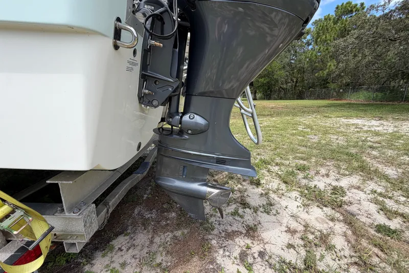 Slide: The Image of Outboard motor of 2022 World Cat 230 DC boat on trailer, grassy background. - 21