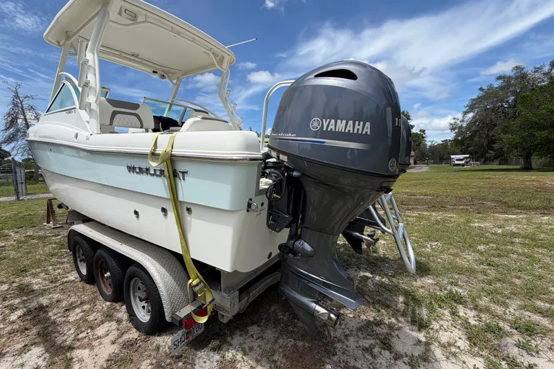 Slide: The Image of 2022 World Cat 230 DC boat on trailer with Yamaha outboard motor, parked on grass. - 15