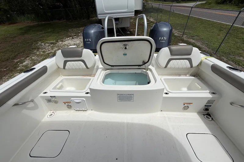 Slide: The Image of 2022 World Cat 230 DC boat interior with open storage compartments and twin Yamaha 115 engines. - 54