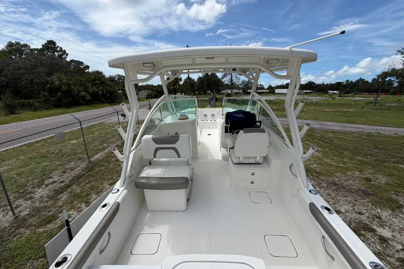 Slide: The Image of 2022 World Cat 230 DC boat interior with seating and helm, parked on grassy area. - 37