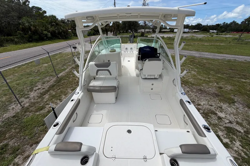 Slide: The Image of 2022 World Cat 230 DC boat interior with seating and helm, parked on grass. - 36