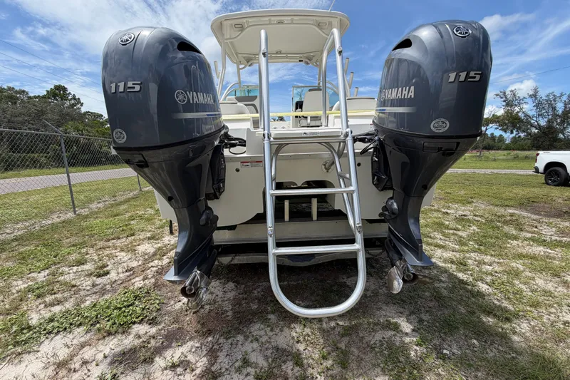 Slide: The Image of 2022 World Cat 230 DC boat with dual Yamaha 115 engines and ladder, parked on grass. - 16