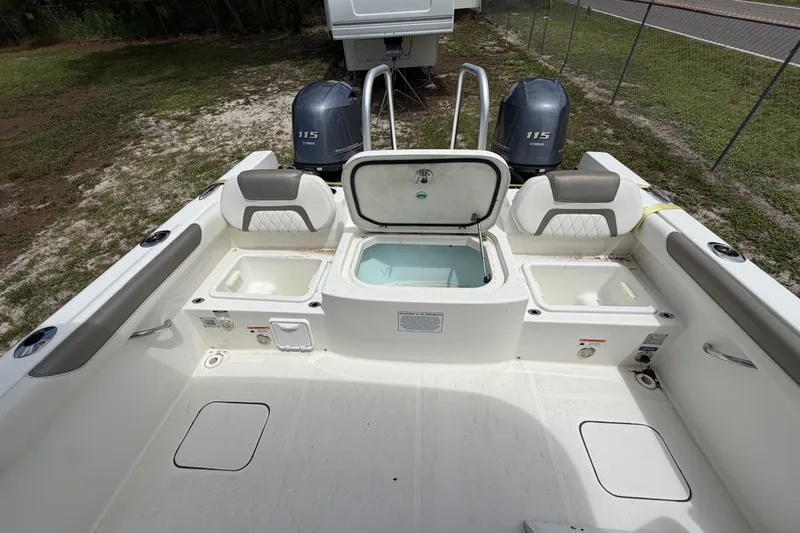 Slide: The Image of 2022 World Cat 230 DC boat interior with open compartments and twin Yamaha 115 engines. - 55